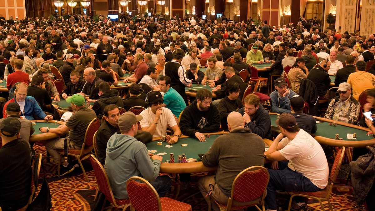 A crowded live poker tournament floor contrasting with the quieter online numbers