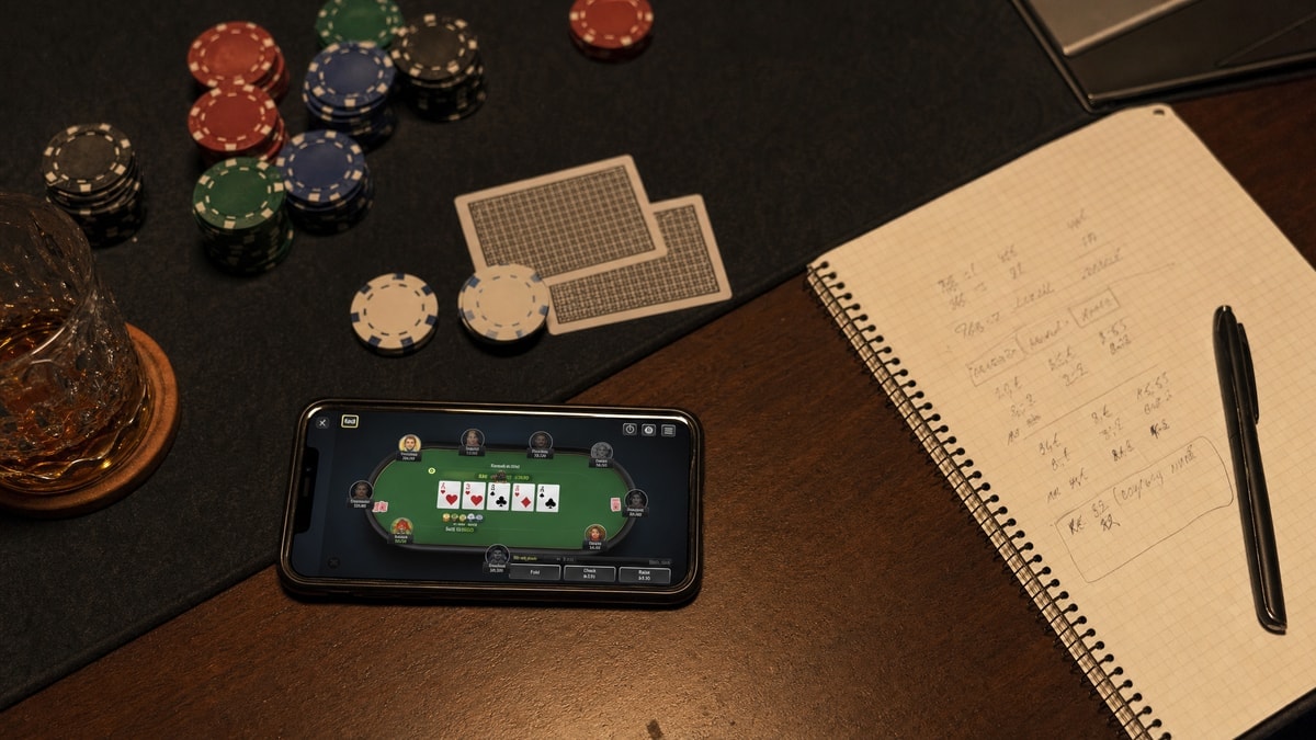 A late-night home online poker grinding setup with phone and notebook